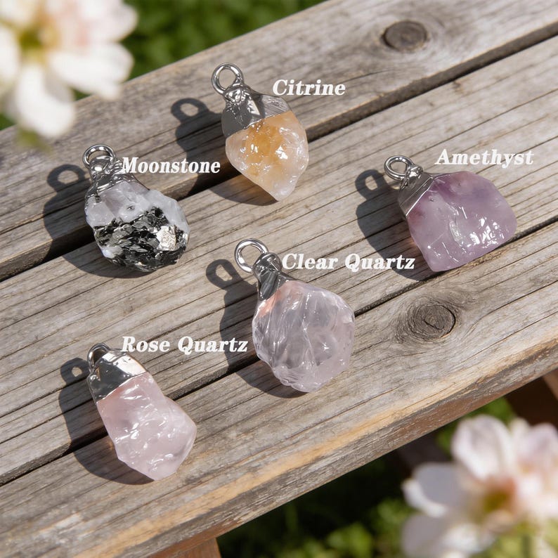 May include: Five gemstone pendants: Citrine, Moonstone, Amethyst, Clear Quartz, and Rose Quartz. Each stone has a unique shape, with a silver-coloured metal cap and loop. The Citrine is yellow, the Amethyst is purple, and the Rose Quartz is pink.