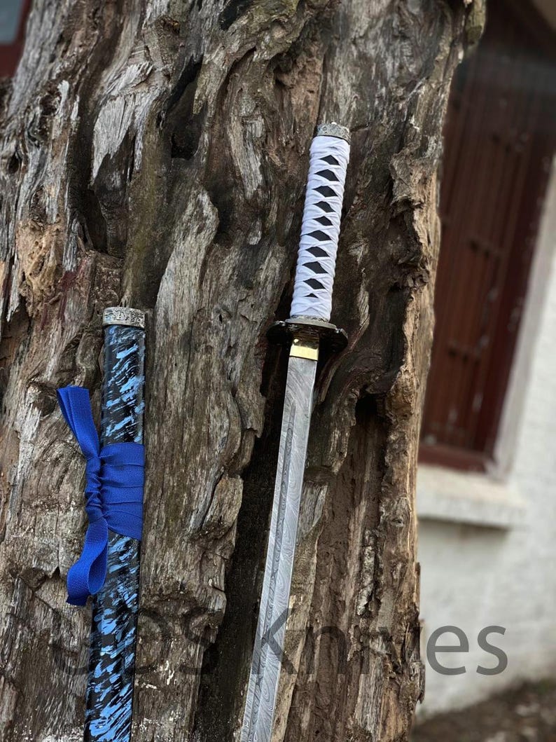 May include: A katana sword with a white wrapped handle and a patterned blade. The scabbard is black and blue with a blue ribbon tied around it. The sword is displayed against a textured tree trunk.