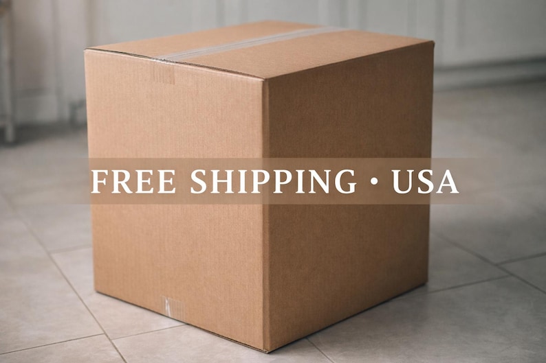 May include: A large, unopened cardboard box, sealed with tape. The box is a light brown color and sits on a tiled floor. The text "FREE SHIPPING &bull; USA" is overlaid on the box.
