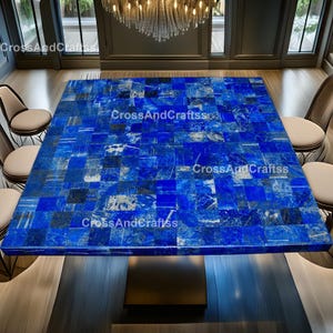 May include: A square dining table with a mosaic tabletop made of deep blue stone tiles. The table is supported by a dark, rectangular base. The room features chairs, a chandelier, and the text "CrossAndCraftss".