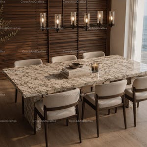 May include: A modern dining room set with a large rectangular marble-look table and six upholstered chairs. A black chandelier hangs above the table. A decorative plant in a dark pot sits in the corner. The room has a view of the ocean.