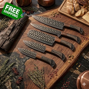 May include: A set of five kitchen knives with textured blades and wooden handles, arranged on a wooden cutting board. The knives vary in size and shape, with a leather knife roll on the left. The blades have a hammered finish.