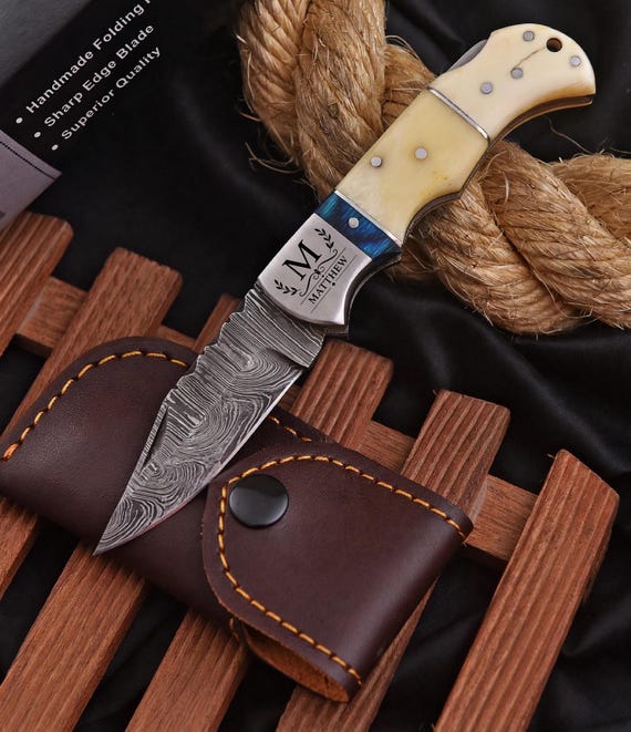 Damascus steel folding knife with a camel bone handle — the layered steel patterning and exotic handle material make this genuinely handcraft-feeling and visually striking.