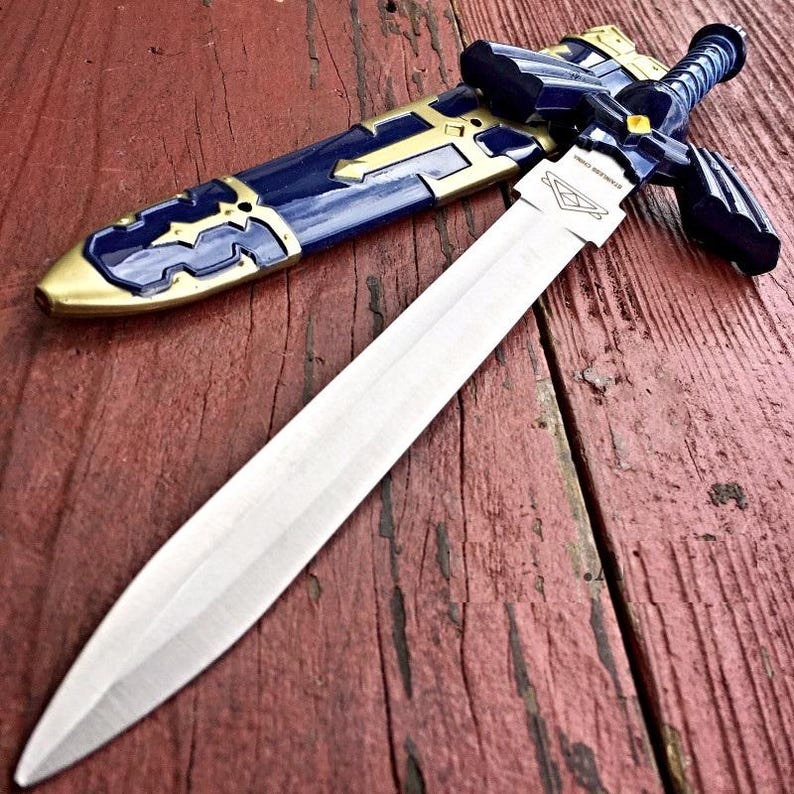 May include: A silver-bladed sword with a blue and gold hilt and scabbard. The sword is on a weathered, red wooden surface. The scabbard is blue with gold accents. The hilt is blue with a silver crossguard.