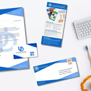 Op de afbeelding: Briefpapier set met een blauw en wit ontwerp, inclusief een briefhoofd, visitekaartje en envelop. Een toetsenbord, potloden en andere kantoorbenodigdheden zijn ook aanwezig.
