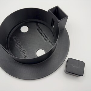 May include: A matte black 3D-printed circular mount for a Dyson Cool Tower Fan with a SwitchBot mount, featuring the text 7eightfive and Dyson Cool Tower Fan AM07 SwitchBot Mount embossed on the base, alongside a small black square SwitchBot device.