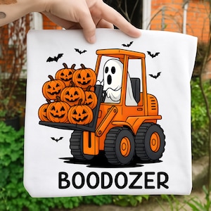 May include: White tote bag with a Halloween design. An orange forklift, driven by a ghost, carries carved pumpkins. Black bats fly around the image, and the word "BOODOZER" is printed at the bottom. A fun, seasonal accessory.