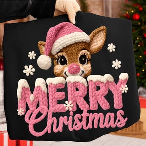 以下が含まれることがあります： ピンクのサンタ帽をかぶったトナカイが描かれた黒いクリスマス枕。 「MERRY Christmas」の文字は、ピンク色のニット風の文字で表示され、白いアクセントが付いています。白い雪の結晶がトナカイとテキストの周りに散らばっています。