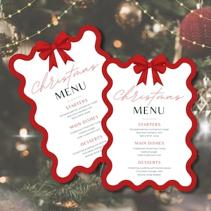 Puede incluir: Dos tarjetas de menú navideño con borde rojo festoneado y lazo rojo en la parte superior. El menú incluye entrantes, platos principales y postres. El texto está en fuente cursiva. El fondo es un árbol de Navidad borroso.