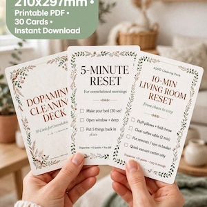 Pode incluir: Três cartões retangulares brancos com bordas botânicas e texto preto. Os cartões são intitulados Dopamine Cleaning Deck, 5-Minute Reset for overwhelmed mornings e 10-Min Living Room Reset from chaos to cozy, com listas de verificação.