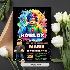 Pu&ograve; includere: Invito nero con un personaggio di Roblox. Il testo include "ROBLOX", "MARIE COMPIE DUE ANNI!" e dettagli dell'evento. Fiori bianchi e busta marrone sullo sfondo. Invito di compleanno.