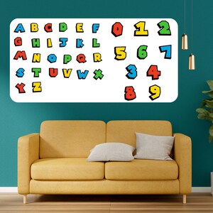 May include: A white rectangular wall decal featuring colorful letters and numbers. The letters A through Z and numbers 0 through 9 are displayed in a playful, cartoon-like font. The decal is mounted on a teal wall above a yellow sofa.