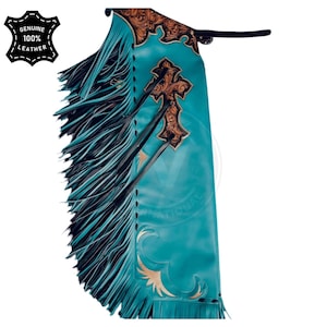 May include: Turquoise leather chaps with brown embossed cross and floral designs. The chaps have long black fringe along the sides and the text "GENUINE 100% LEATHER" on a black patch.