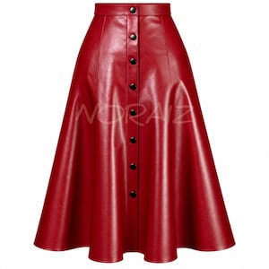 Puede incluir: Una falda midi de corte en A y cintura alta en un color rojo vibrante con un acabado suave similar al cuero. La falda presenta una fila vertical de ocho botones negros en la parte delantera central e incluye el texto NORAIZ en el medio.