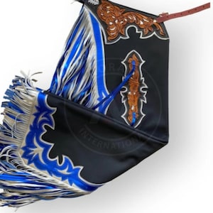 May include: Black leather chaps with brown tooled leather detailing and blue and silver fringe. The chaps have a decorative design and the text "INTERNATIONAL". A brown leather strap is attached.