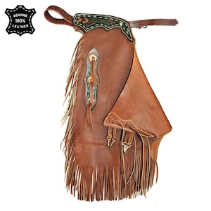 May include: Brown leather chaps with fringe and decorative turquoise and gold accents. The chaps have a belt and are labeled "GENUINE 100% LEATHER".