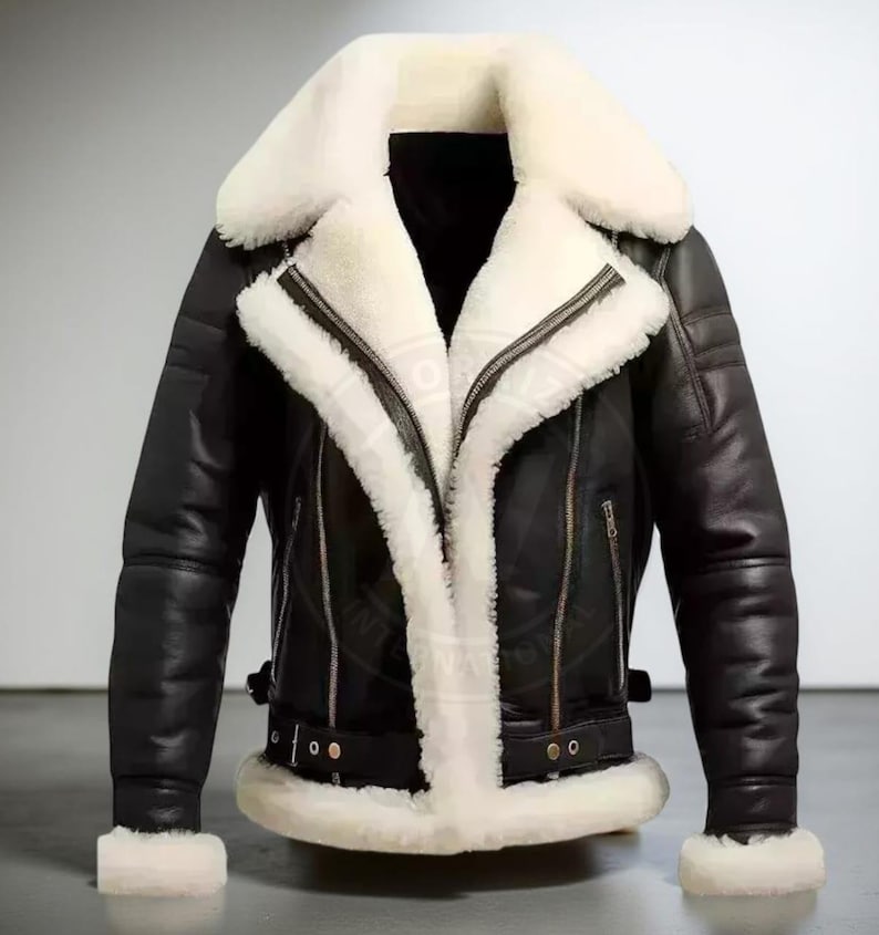 May include: Black leather jacket with a white shearling collar and lining. The jacket features a zip-up front, side pockets, and a buckled belt at the waist. The sleeves have a ribbed design and cuffs with white shearling trim. A classic outerwear piece.