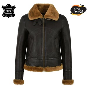 May include: Black leather jacket with a brown shearling collar and trim. The jacket has a zip-up front, two pockets, and a "Genuine 100% Leather" logo. The jacket is a classic style.