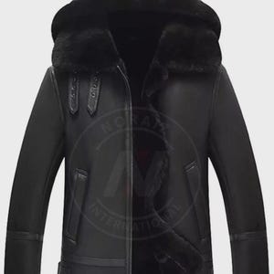 May include: Black leather jacket with a hood and a fur-lined interior. The jacket features a zipper closure, two front pockets, and buckle details on the sleeves. The jacket is designed for cold weather.
