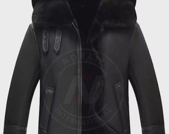 May include: Black leather jacket with a hood and a fur-lined interior. The jacket features a zipper closure, two front pockets, and buckle details on the sleeves. The jacket is designed for cold weather.