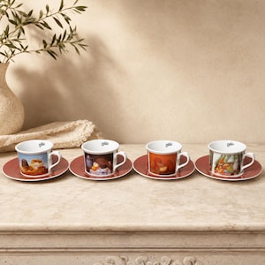 May include: Four white ceramic coffee cups with matching terracotta-colored saucers. Each cup features a unique, colorful illustration of food and kitchen items on the exterior and the word 'Caffè' printed in black on the interior rim.