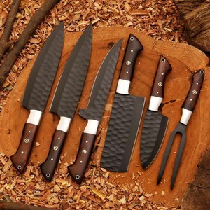 May include: A set of six kitchen knives with dark blades and wooden handles. The blades have a textured surface, and the handles are a dark brown color with silver accents. The set includes a cleaver, chef's knife, and carving fork.