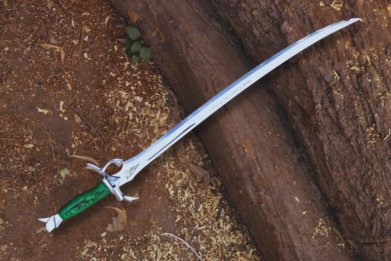 May include: A silver fantasy sword with a curved blade and a green handle. The sword has intricate details on the hilt and blade, and is lying on a wooden surface.