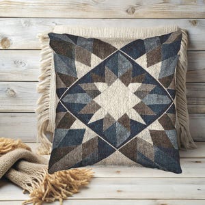 Puede incluir: Cojín decorativo cuadrado con un patrón geométrico de estrella en tonos azules, marrones y crema. El cojín está colocado sobre otro cojín con flecos y una superficie de madera, creando una estética acogedora.