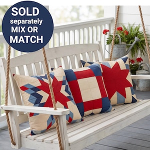 May include: Three decorative throw pillows with red, white, and blue geometric patterns rest on a white wooden swing. The pillows feature star and square quilt designs. The image includes the text "SOLD separately MIX OR MATCH" in a navy blue circle.