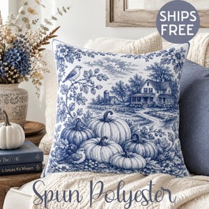 Puede incluir: Un cojín cuadrado con un patrón de toile de Jouy en azul y blanco. El diseño muestra un paisaje rural con una granja, un silo, calabazas y pájaros posados en ramas. La tela presenta un estampado monocromático detallado sobre fondo blanco.
