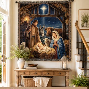May include: A rectangular woven wall tapestry featuring a nativity scene with a central infant in a manger, a man holding a staff, and a woman in a blue head covering. The scene includes a donkey, an ox, and sheep under a bright star.