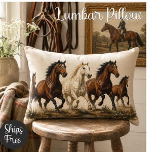 Op de afbeelding: Rechthoekig lendenkussen met een gedetailleerde schildering van rennende paarden in bruin en wit. Het kussen ligt op een houten kruk. De tekst "Lumbar Pillow" staat bovenaan.