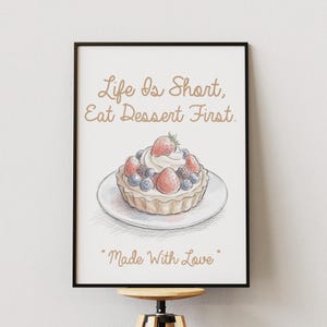 Peut inclure: Impression encadrée avec une illustration à l'aquarelle d'une tarte aux fruits sur une assiette blanche. La tarte est garnie de fraises, de myrtilles et de crème fouettée. Le texte dit "Life Is Short, Eat Dessert First" et "Made With Love."
