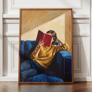Peut inclure: Une peinture à l'huile dans un cadre en bois représentant une personne portant un pull en tricot torsadé jaune moutarde et un jean bleu, assise sur un canapé bleu profond tout en tenant un livre rouge ouvert devant son visage, sur un mur jaune.