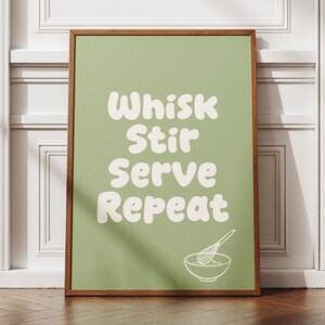 Peut inclure: Une affiche murale rectangulaire dans un cadre en bois avec un fond vert sauge, le texte blanc Whisk Stir Serve Repeat et un dessin au trait blanc représentant un fouet dans un bol à mélanger situé dans le coin inférieur droit.