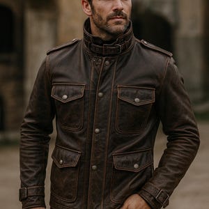 Puede incluir: Chaqueta de cuero marrón con cuello alto y múltiples bolsillos. La chaqueta tiene un aspecto robusto con botones y hebillas. Las mangas tienen un ajuste a medida y la chaqueta parece estar bien construida.