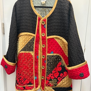 May include: A quilted jacket featuring a color-blocked design in black, red, and gold. The garment has a round neckline, long sleeves with folded cuffs, and a front button closure. The fabric displays various textures and patterns.