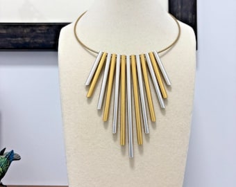 Gargantilla colgante estilo años 80 con diseño de tubo de órgano en tonos plateados y dorados.