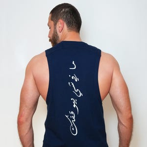 May include: Navy blue sleeveless shirt with white Arabic script down the back. The shirt is a solid color and appears to be made of a soft material. The shirt is worn by a person.