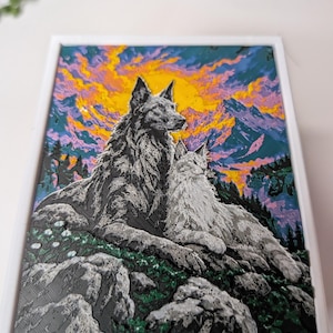 May include: A rectangular framed art piece featuring a greyscale illustration of two wolves resting on a rocky, green-foliaged hillside. The background displays a vibrant, textured sunset with yellow, orange, and purple clouds over mountain peaks.