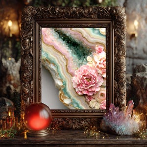 May include: A framed artwork featuring a geode design with pink, green, and gold layers, adorned with pink floral accents. The ornate, dark brown frame complements the artwork's colors. A red crystal ball and a cluster of crystals are in the foreground.