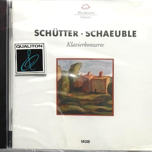 Puede incluir: Una caja de CD con el álbum "Schütter Schaueble Klavierkonzerte". La portada presenta una pintura de edificios y árboles. El logotipo de Qualiton está en el lado izquierdo.