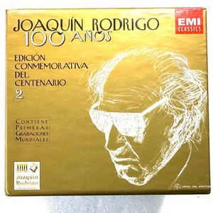 May include: A gold-coloured box set with a portrait of a man wearing glasses. The text reads "JOAQUÍN RODRIGO 100 AÑOS" and "EDICIÓN CONMEMORATIVA DEL CENTENARIO 2." The EMI Classics logo is visible.