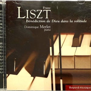 May include: A CD case with the title "LISZT" in white lettering, and the French title "Bénédiction de Dieu dans la solitude". The cover features a piano keys design, with the artist Dominique Merlet's name. The CD is part of the "COLLECTION ÉLÉVATION" series.