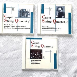 May include: Three CD cases featuring the "Capet String Quartet" series. Each case has a white background with blue accents and text. The CDs feature images of musicians and composers, with titles like "Haydn 'Lark'" and "Mozart Dissonance."