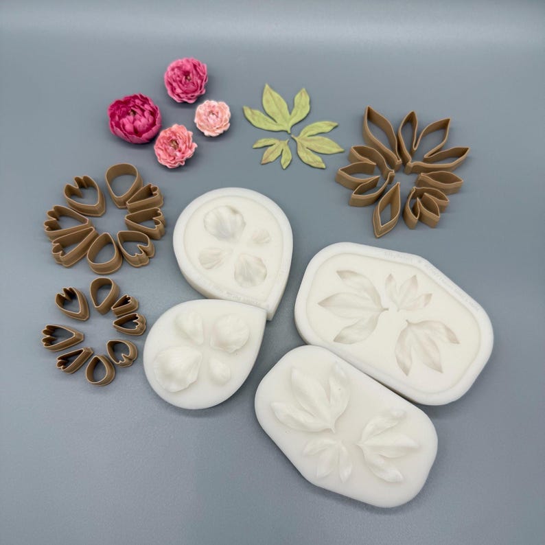 May include: A collection of crafting tools including three white silicone molds with petal and leaf impressions, four brown plastic petal and leaf cutters, three small pink peony-like flowers, and three light green leaf cutouts.