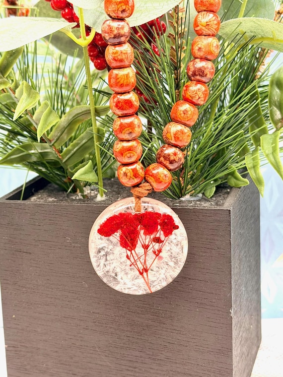 Beaded necklace featuring a selenite pendant, red baby breath, pressed flowers, and wooden beads.