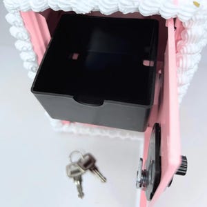 Close-up of the inside compartment of the pink cake vault mini locker, showing coin basket and roomy space for cash, jewelry, or small treasures.
