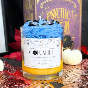 Coraline Halloween Candle with unique Coraline label, yellow layers, black button details, and blue whipped cream top – spooky soy wax candle for Coraline fans.