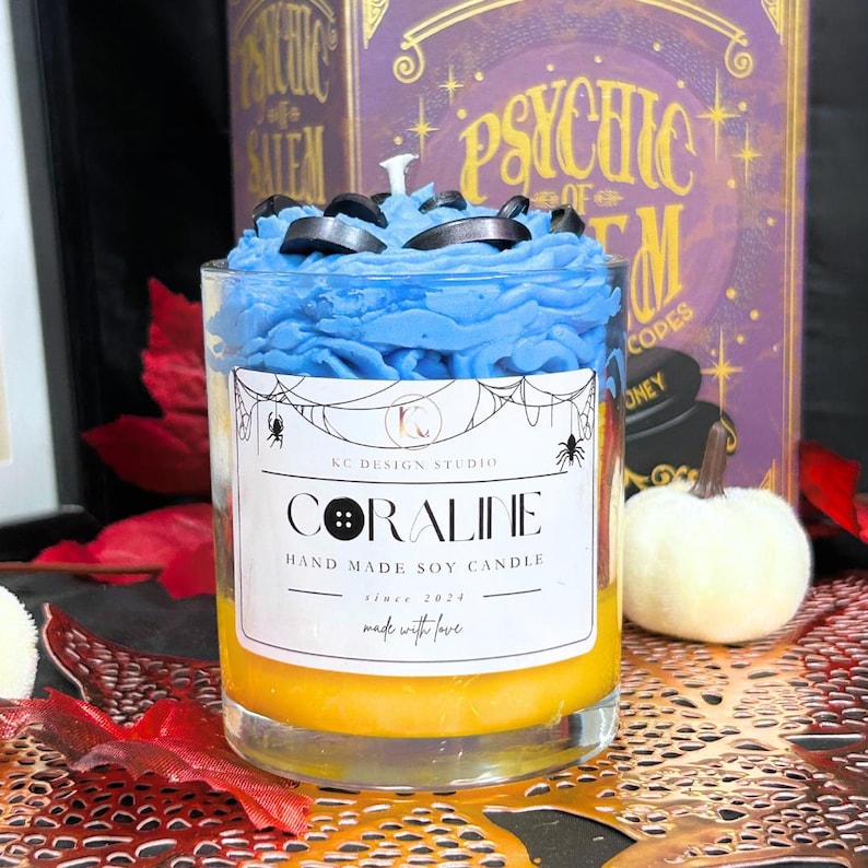Coraline Halloween Candle with unique Coraline label, yellow layers, black button details, and blue whipped cream top – spooky soy wax candle for Coraline fans.